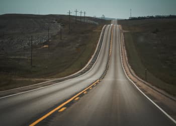 Scenic view of a long, winding highway in a rural landscape under a clear sky.
