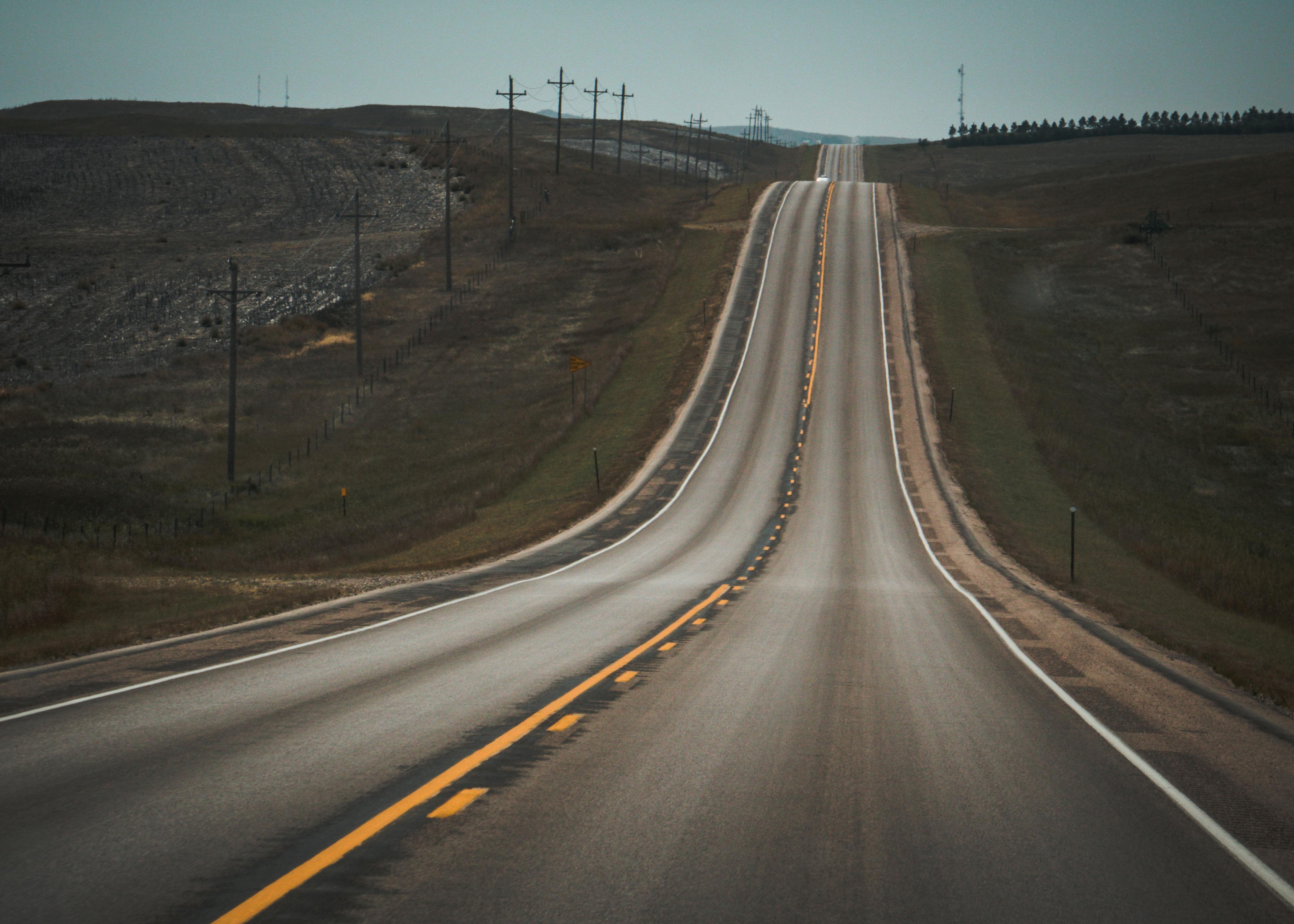 Scenic view of a long, winding highway in a rural landscape under a clear sky.