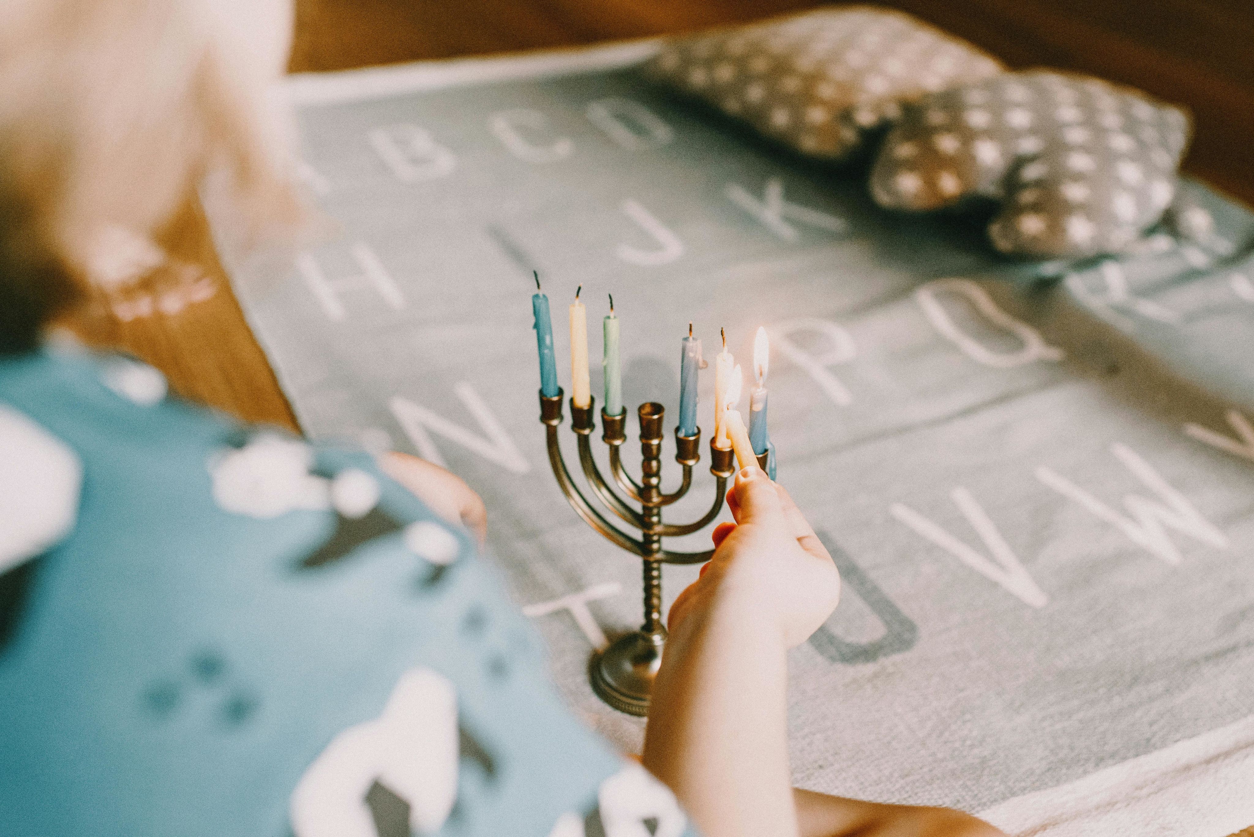 A child lights a menorah indoors, celebrating Hanukkah with tradition.